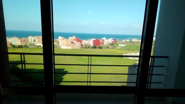 A balcony with a view of a grassy area and buildings in the distance. - Ocean Atlantic Residence 1512 (Asilah)