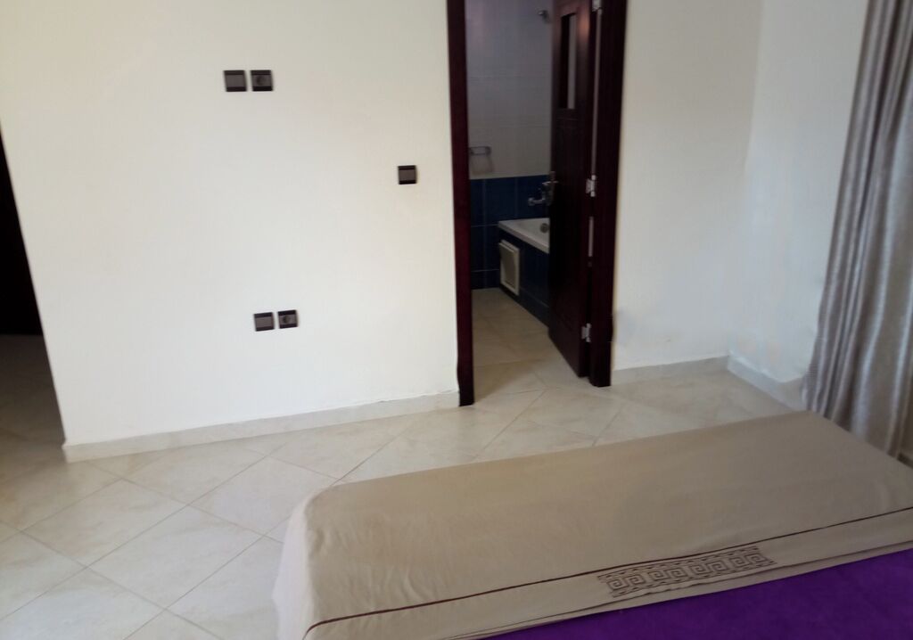 A room with a bed, a door leading to a bathroom, and a small kitchenette.