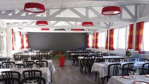 A dining area with multiple tables set for service, featuring a modern design with red accents and a neutral color palette. - Village de vacances de Marc - Chambres (Auzat)