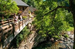 Un edificio de piedra con una terraza de madera que da a un arroyo rocoso.