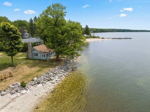 A lakeside property with a stone house, a picnic table, and a clear view of the lake.
