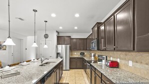 Una cocina moderna con encimeras de granito, electrodomésticos de acero inoxidable y armarios de madera oscura.