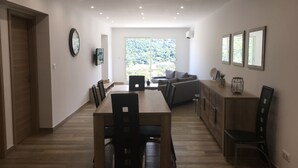 Un comedor amplio con una mesa y sillas de madera, un sofá, y una zona de cocina con armarios y encimera.