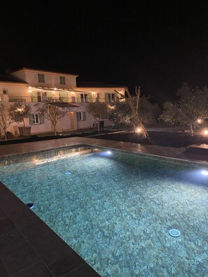 A swimming pool with clear water, surrounded by a tiled deck.