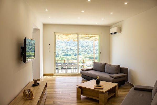 A modern living room with a sofa, a coffee table, and a TV mounted on the wall.