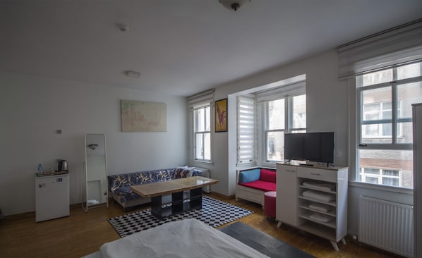 Cozy retreat with a bed, kitchenette, and TV, offering a view of the outside.