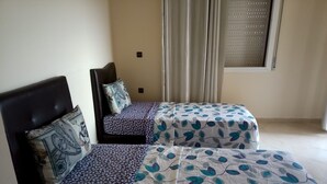 Ein Zimmer mit zwei Betten, jeweils mit gemusterten Bettbezügen.