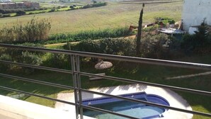 Blick vom Balkon auf einen Pool, eine Wiese und ein Gebäude im Hintergrund.