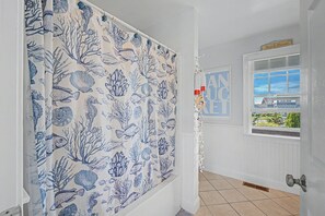 A hallway with a white door, a window with a view of a house, and a curtain with an underwater theme. - Views! Four bedroom sleeping 8 with views of West Dennis Beach (West Dennis)