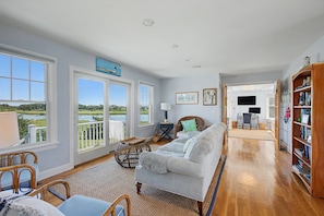 A spacious living room with a view of a lake, a dining area, and a library. - Views! Four bedroom sleeping 8 with views of West Dennis Beach (West Dennis)