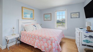 Un dormitorio con cama, mesita de noche, cómoda, ventana y decoración en la pared.