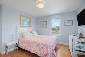 Un dormitorio con cama, mesita de noche, cómoda, ventana y decoración en la pared.