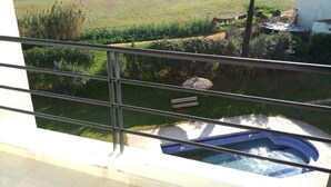 A balcony with a view of a swimming pool and a field.