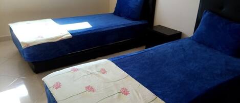 A room with two beds, each with a blue bedspread and a white pillow with a floral pattern.