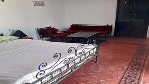 Una habitación con una cama, un sofá rojo y una puerta negra.