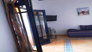 Una sala de estar con sofá, televisión y alfombra estampada.