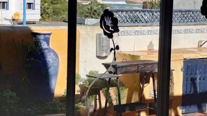 Eine Terrasse mit einer großen, blauen Vase, einem Metalltisch und einem Stuhl.