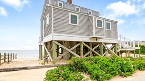 Ein Strandhaus mit einer Holzterrasse und Blick aufs Meer.