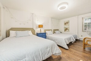 A room with two beds, a nightstand, a lamp, and wall art.