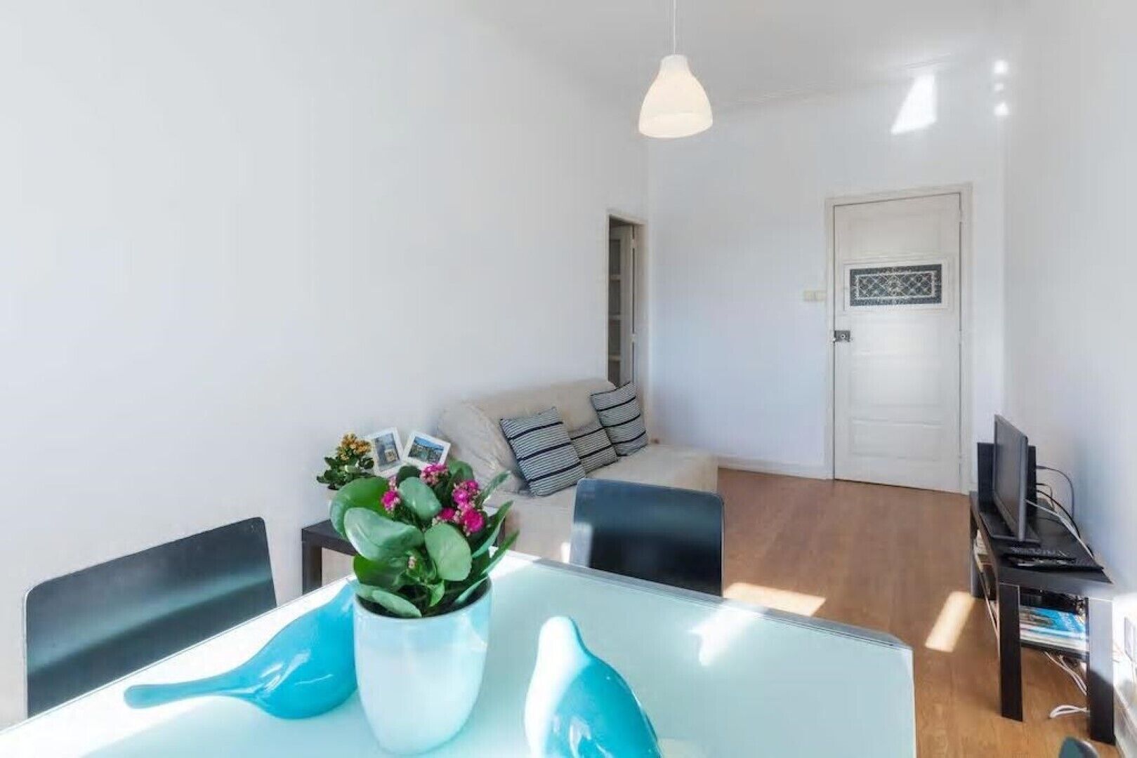 Una sala de estar moderna con una mesa de comedor, sillas, un sofá, un televisor y una puerta con un diseño decorativo.
