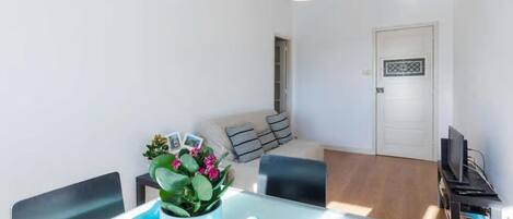 Una sala de estar moderna con una mesa de comedor, sillas, un sofá, un televisor y una puerta con un diseño decorativo.
