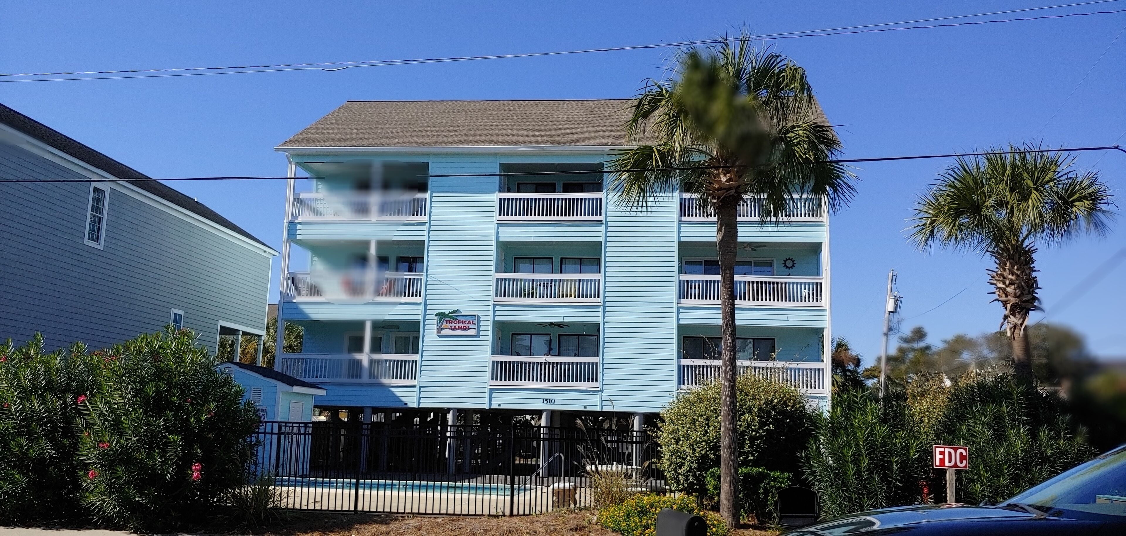 A multi-story hotel with balconies, a pool, and a tropical theme sign.
