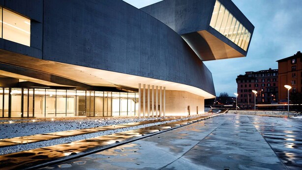 Un edificio moderno con una facciata curva e una sporgenza ampia.