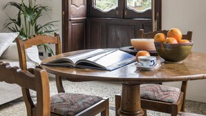 Un tavolo di legno con un libro, una ciotola di arance, una candela e una tazza.
