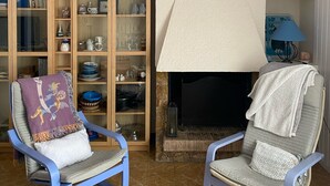 A living room with two blue armchairs, a fireplace, and a bookshelf filled with decorative items. - Mediteranean Sweet & Suite (Palafrugell)