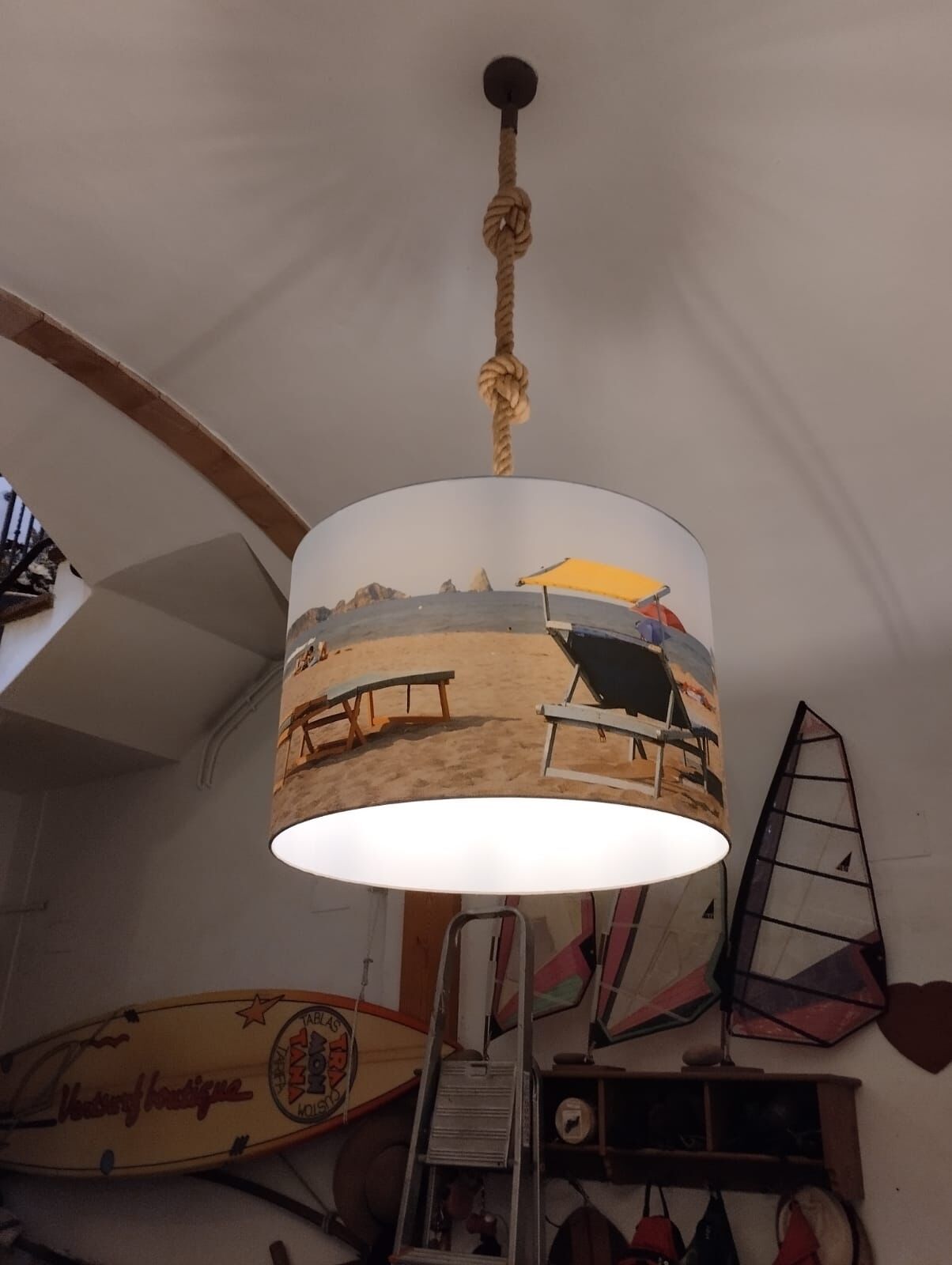 A beach-themed pendant light hanging from a ceiling with a rope.