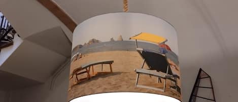 A beach-themed pendant light hanging from a ceiling with a rope.