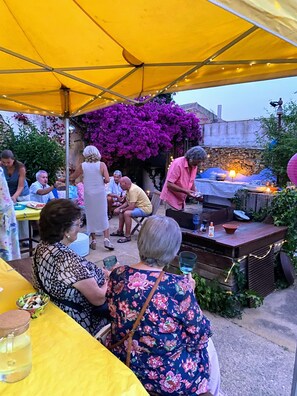 An outdoor patio area with a yellow canopy, a stone wall, and purple bougainvillea flowers. - Mediteranean Sweet & Suite (Palafrugell)