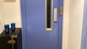 A blue door with a vertical window, a small plaque, and a wheelchair accessibility sign. - Mediteranean Sweet & Suite (Palafrugell)