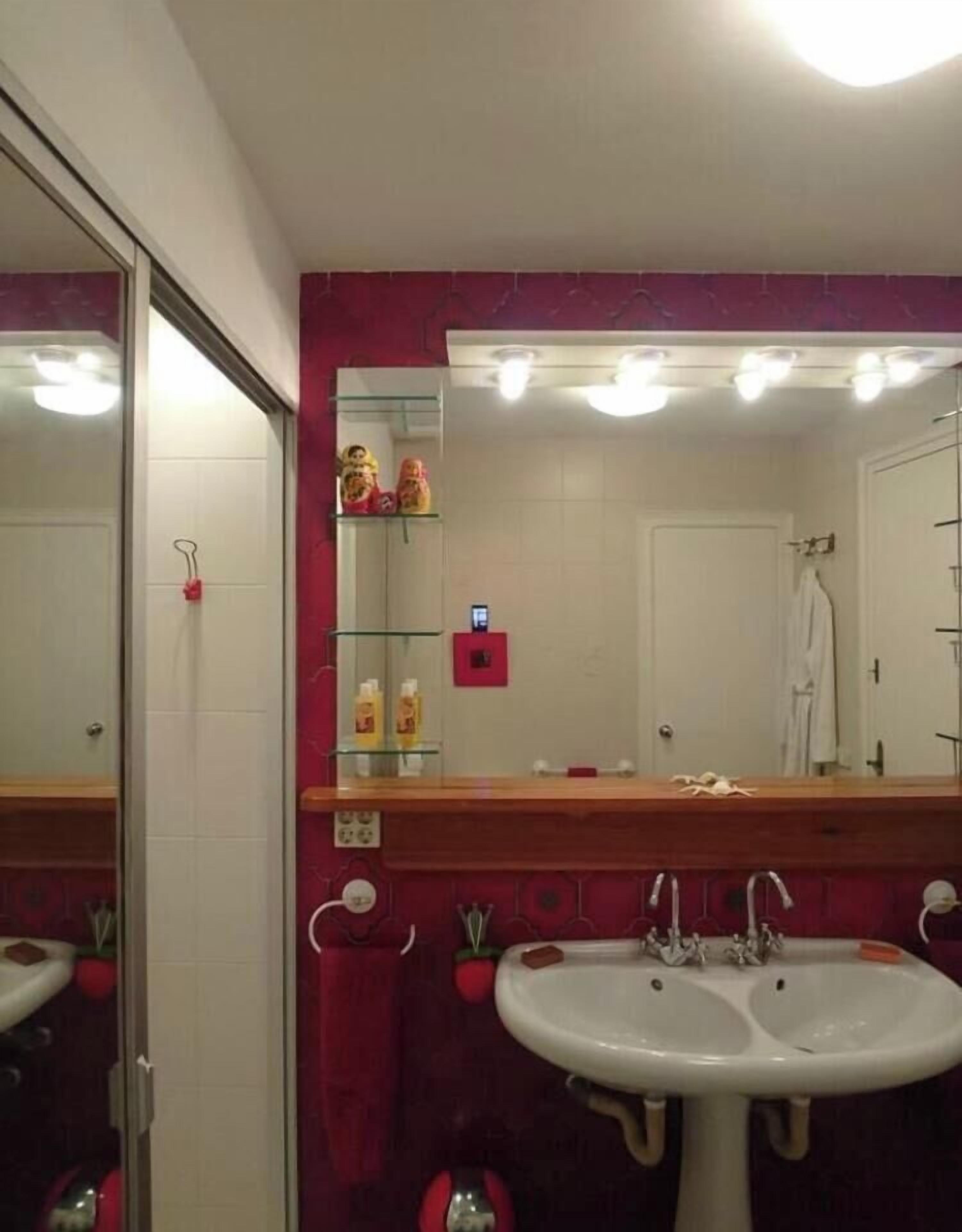 Une salle de bain avec un double vasque, un miroir et un mur d’accent de couleur rouge.