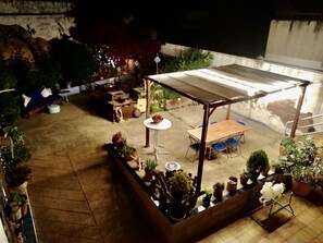 An outdoor patio area with a covered seating area, a table, and various potted plants. - Mediteranean Sweet & Suite (Palafrugell)