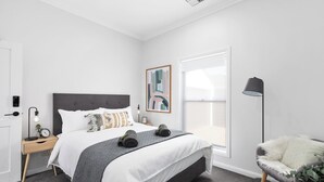 A modern bedroom with a bed, bedside table, lamp, and a view of the outdoors. - The Abode - Luxury, centrally located, 10 guests. (Mount Gambier)