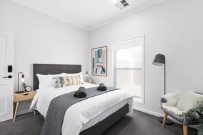 A modern bedroom with a bed, bedside table, lamp, and a view of the outdoors. - The Abode - Luxury, centrally located, 10 guests. (Mount Gambier)