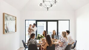 Un comedor moderno con una lámpara de techo geométrica, un ventanal grande y una obra de arte enmarcada en la pared.