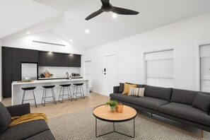 Een moderne woonruimte met een keuken, barstoelen, een bank en een salontafel.