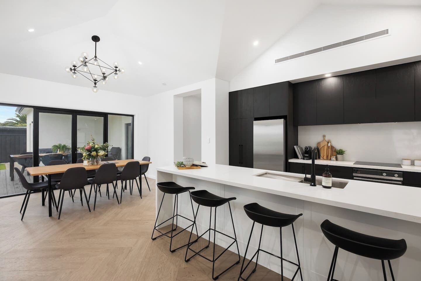 A modern kitchen with dark cabinets, a stainless steel refrigerator, and a white countertop.
