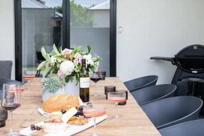 Een buitentafel gedekt met bloemen, wijn glazen en verschillende soorten eten.