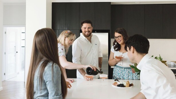 A modern kitchen with a central island, dark cabinetry, and a white countertop. - The Abode - Luxury, centrally located, 10 guests. (Mount Gambier)