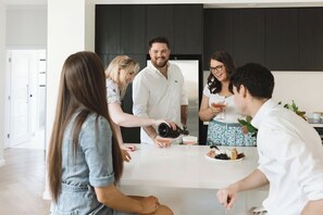 Una cocina moderna con una isla central, armarios oscuros y encimera blanca.