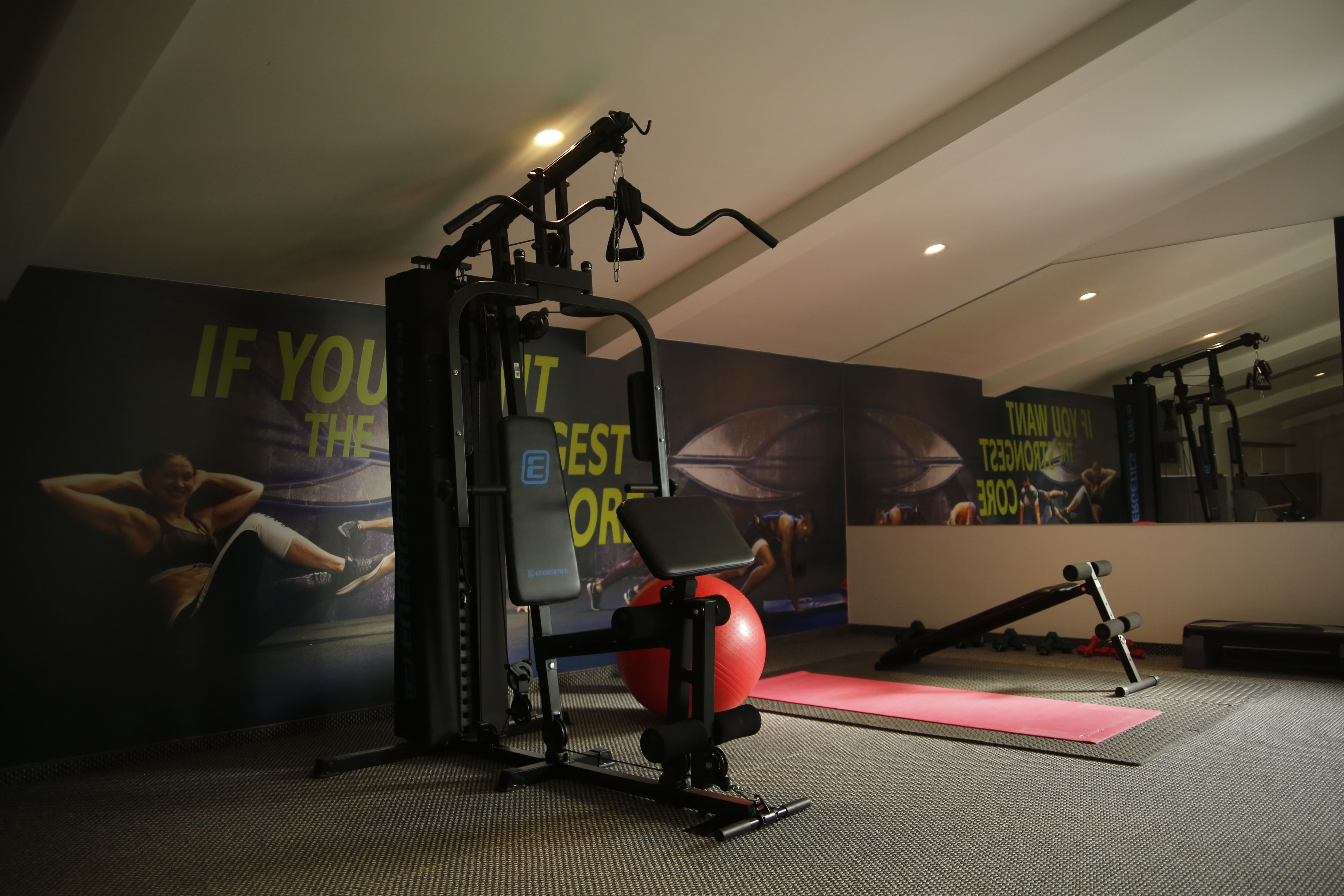 A gym with exercise equipment, a red exercise ball, and motivational posters on the wall.