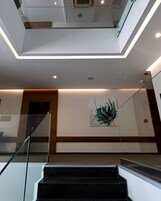 Un interior moderno con una escalera de cristal, una lámpara de techo y una obra de arte colgada en la pared.
