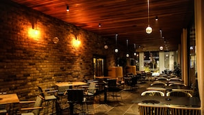 Un restaurante con paredes de ladrillo, techo de madera y varias mesas y sillas.