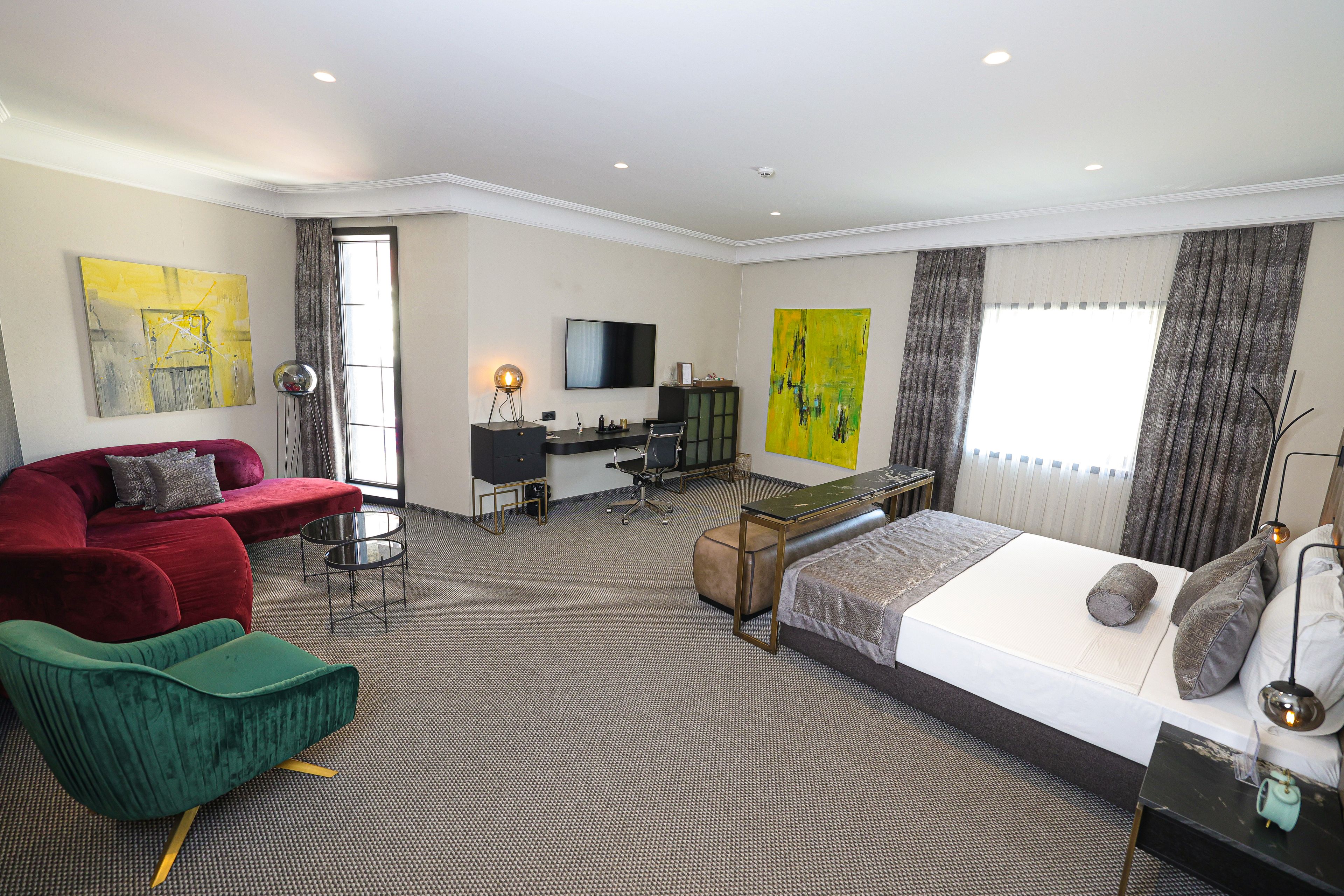 A modern hotel room with a bed, a desk, a TV, and a sofa.