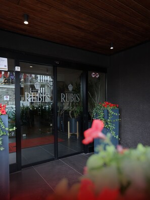 A hotel entrance with a glass door, a wooden ceiling, and potted plants. - Hotel Rubis (Ferizaj)