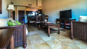 A spacious living room with a high ceiling, a television, and a dining area with chairs and a table. - "SLOW M’OCEAN VIEWS"  Golf Course & Resort (Roatan)