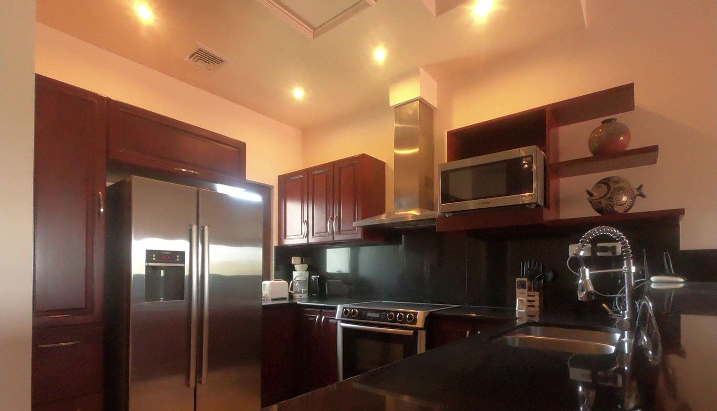 A modern kitchen with stainless steel appliances, wooden cabinets, and a black granite countertop.